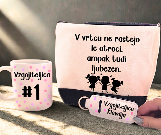 Darilni komplet za vzgojiteljico – skodelica z napisom “Vzgojiteljica #1”, peresnica z motivom otrok in citatom o ljubezni ter personaliziran ETUI z imenom, v nežnih rožnatih tonih.